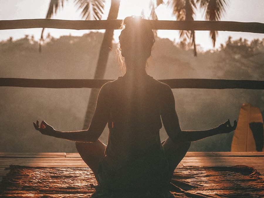 Persoană meditând în lumina apusului